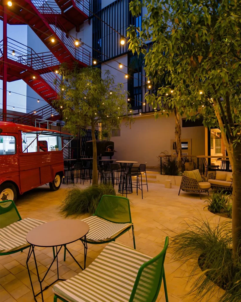 Patio de la terrasse La Pla7 avec Citroën HY rouge, escalier métallique et guirlandes lumineuses à Tunis